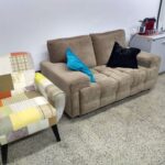 Sofá e poltrona, com almofadas e máquina de café espresso.